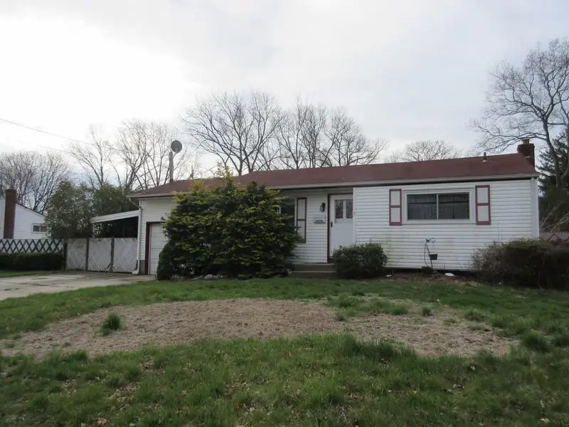 Ranch behind an overgrown lawn with a dirt patch, Brentwood, NY